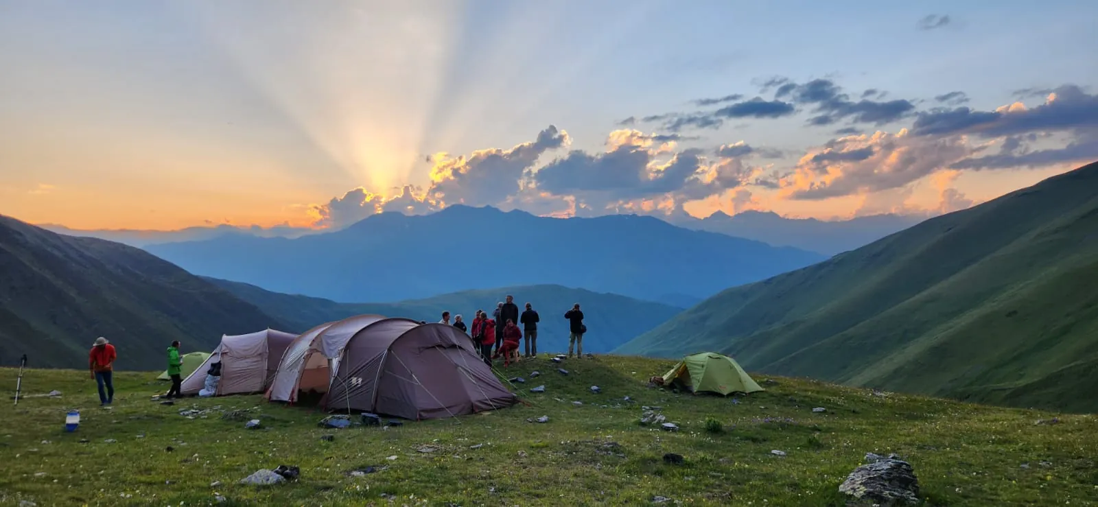 Hikers and tents on a ridge at sunset