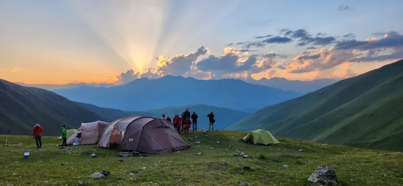 Hikers and tents on a ridge at sunset